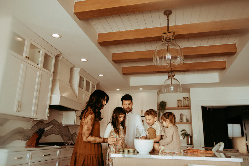 Family gathered around the counter mixing muffins at an in-home photography session.