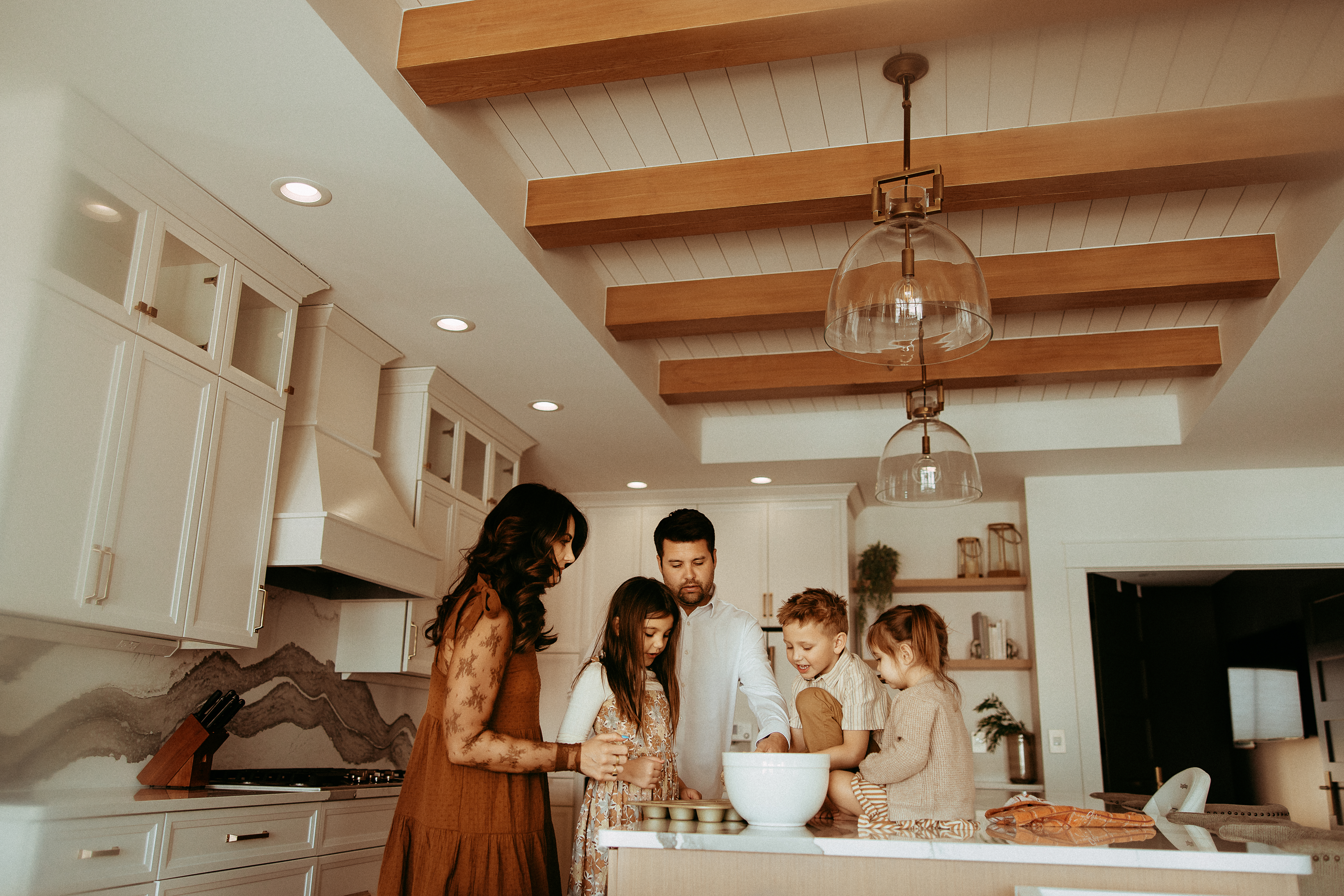 Family gathered around kitchen countertop mixing muffins together at an in-home family photography session.